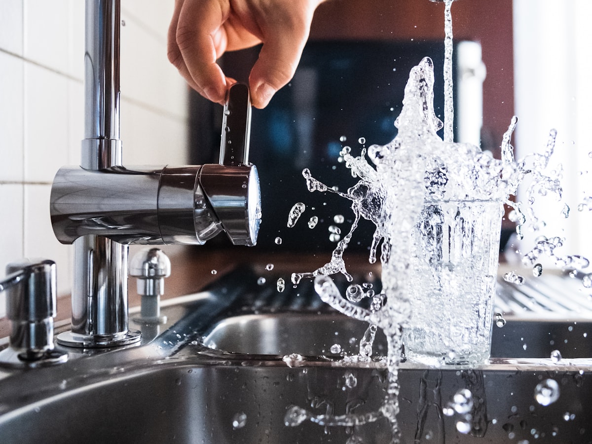 Kitchen mixer tap running with water splashing into the sink