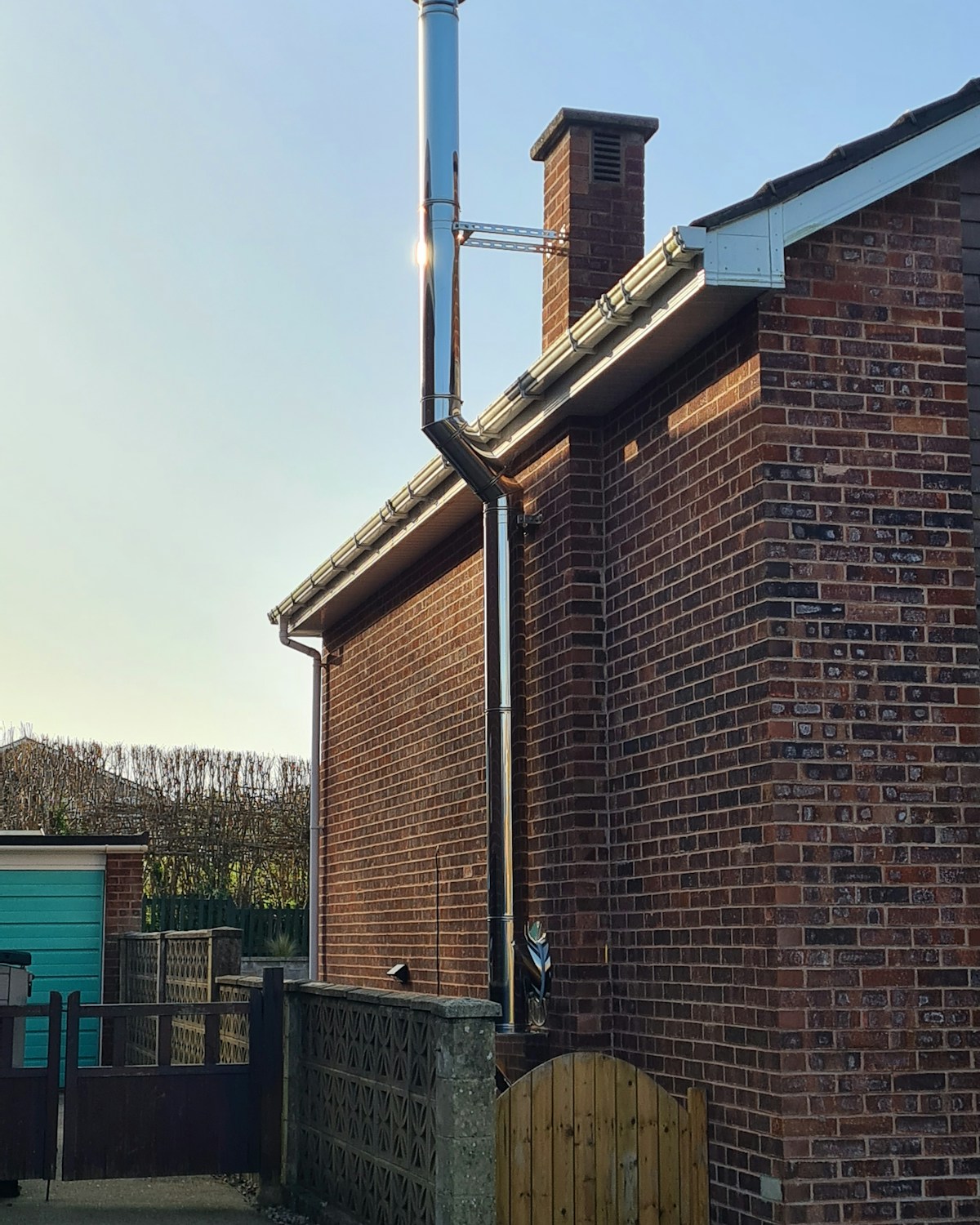 New stainless steel boiler flue fitted to the end wall of a brick terrace